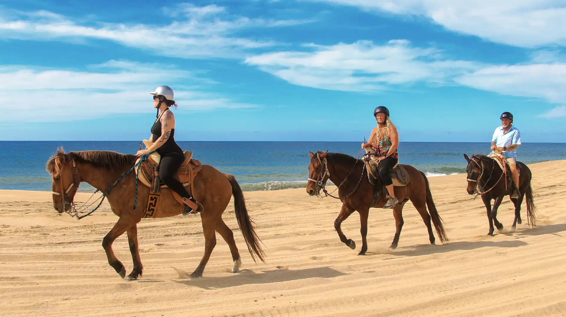 Grupo de personas montando a caballo por la playa durante un tour guiado junto al mar.