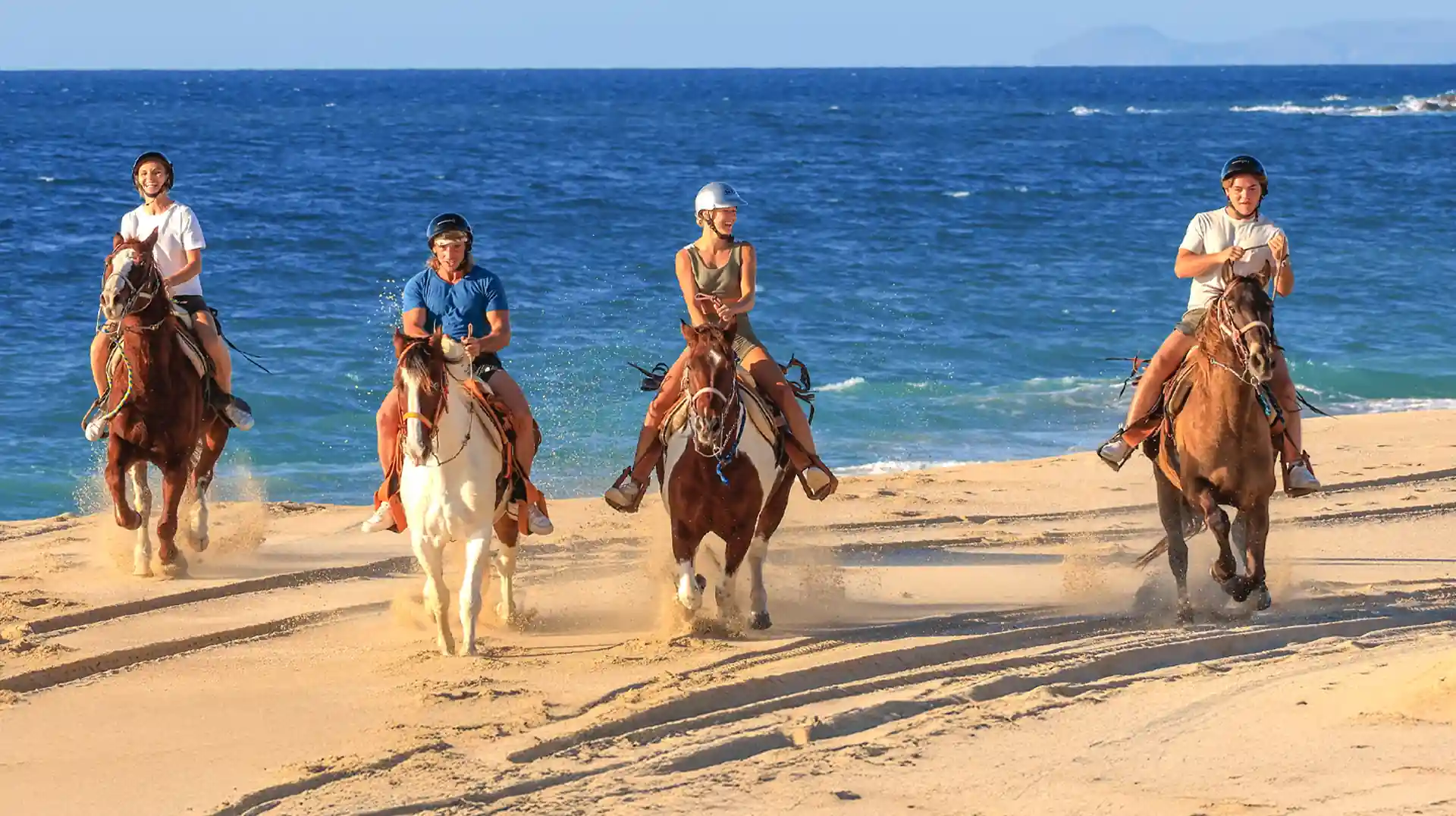 Grupo de personas montando a caballo en la playa de Los Cabos.
